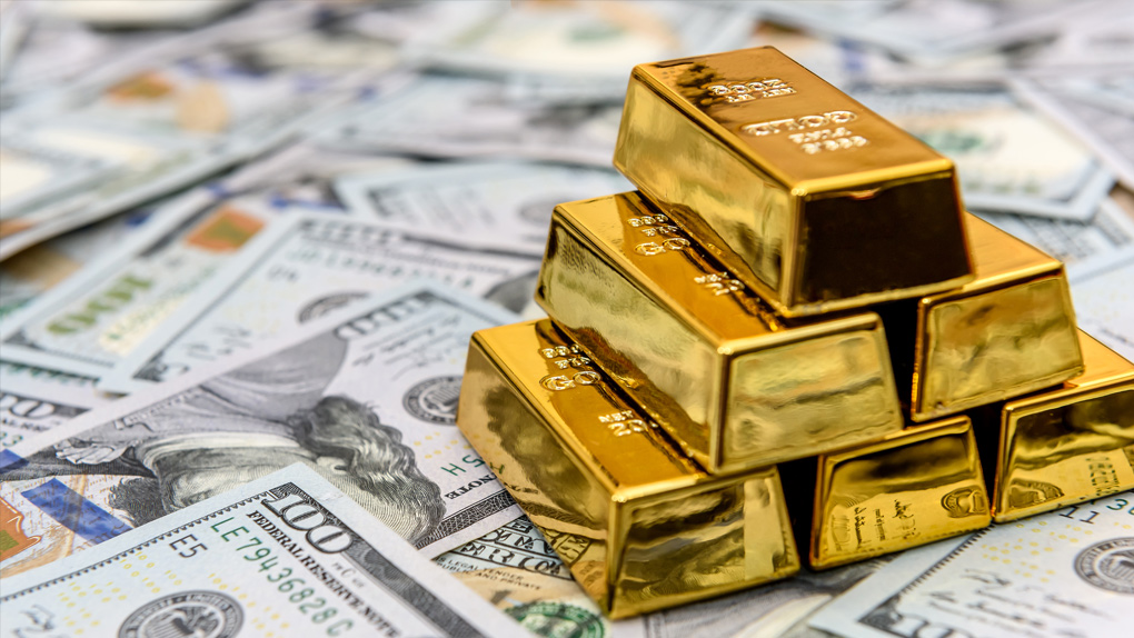 Goldbarren aufgestapelt auf Dollarscheinen